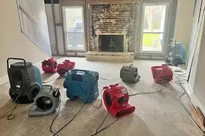 Air movers and two dehumidifiers running across a living room floor after a leak